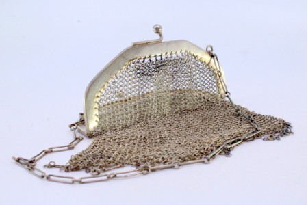 Bolsa de mão em malha de prata com arco liso, franjas em suspensão e corrente em malha cadeado.