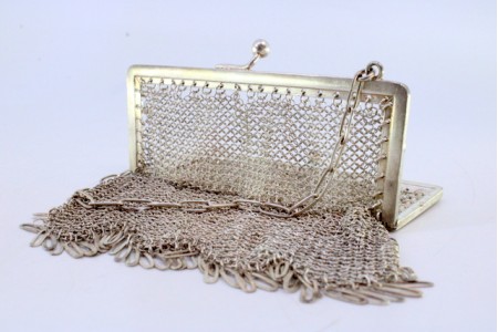 Bolsa de mão em malha de prata com franjas pendentes, arco liso e corrente em malha cadeado.