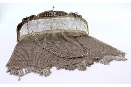Bolsa de mão em malha de prata com relevos florais revelados, franjas suspensas e corrente em malha cadeado.