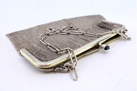 Bolsa de mão em malha de prata com arco liso, dois cabochões azuis no fecho e corrente em malha cadeado.