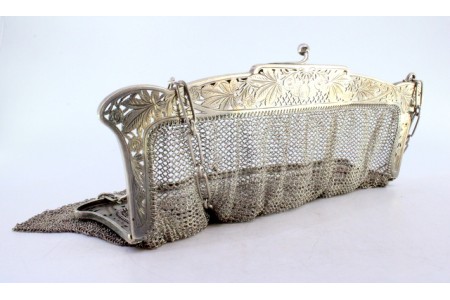 Bolsa de mão em malha de prata com motivos florais recortados no arco e corrente em malha cadeado.