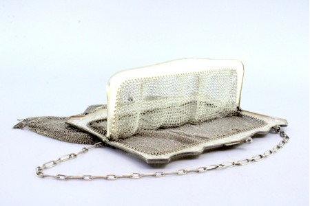  Bolsa de mão em prata com franjas pendentes, arco com motivos florais relevados, duas divisórias e corrente em malha cadeado.