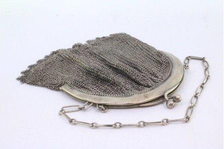 Bolsa de mão em malha de prata com o arco liso, franjas pendentes e corrente em malha cadeado.