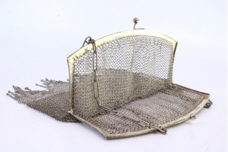 Bolsa de mão em malha de prata lisa com arco liso, franjas suspensas e corrente em malha cadeado.