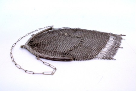 Bolsa de mão em malha de prata com franjas pendentes, arco com duplo friso e corrente em malha de cadeado.