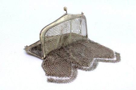 Bolsa de mão em malha de prata com arco liso, franja pendente e corrente em malha cadeado.