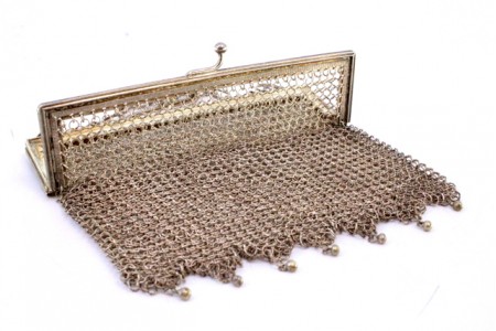 Bolsa de mão em malha de prata com franjas e bolas suspensas, arco com friso duplo e corrente em malha cadeado.