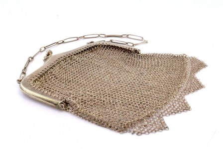 Bolsa de mão em malha de prata com arco liso, franjas pendentes e corrente em malha cadeado.