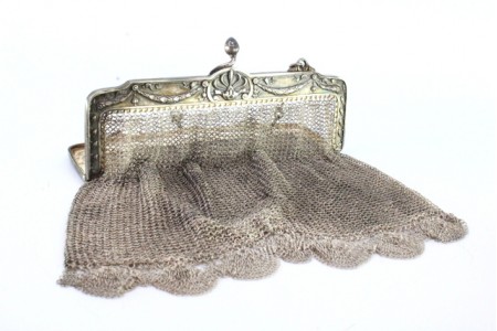 Bolsa de mão em malha de prata com arco com revelado e franjas suspensas com corrente em malha cadeado.