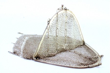Bolsa de mão em malha de prata com arco frisado, franjas em suspensão e corrente em malha cadeado.