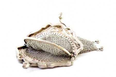Porta moedas em malha de prata com duas divisórias e arco relevado com figuras femininas, fecho em forma de bolotas.