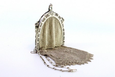 Bolsa de mão em prata com franjas pendentes e relevos no arco. corrente em malha de corrente.