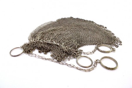  Bolsa de mão em prata em forma de saco com franjas pendentes e corrente com aneis em malha cadeado.