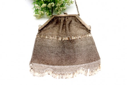 Bolsa de mão em prata com franjas e arco frisado, em malha alternada.