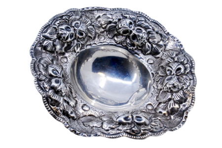 Bomboneira em prata com relevos e aplicações com motivos florais e três pés de apoio.