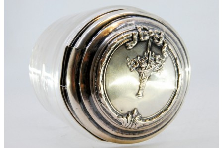 Bomboneira em vidro lapidado e tampa em prata relevada com laço e cesto de flores.