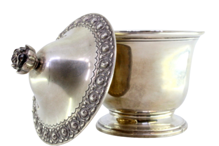 Bomboneira em prata lisa com tampa e pomo relevados com motivos florais, gravados ondeados na base redonda.