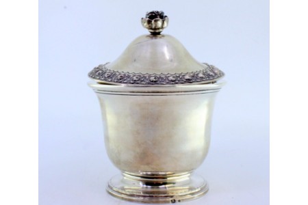 Bomboneira em prata lisa com tampa e pomo relevados com motivos florais, gravados ondeados na base redonda.