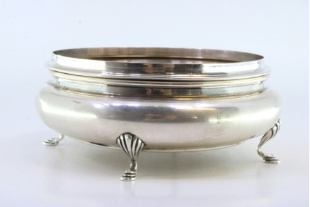 Bomboneira em prata de formato circular com motivos florais revelados na tampa e assente em quatro pés.