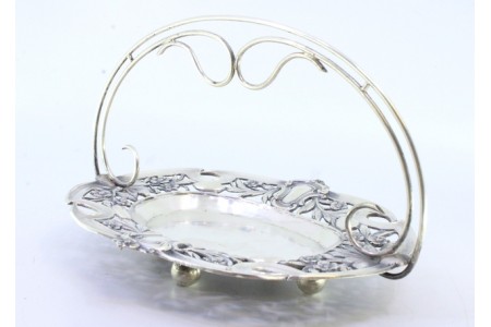 Bomboneira em prata com motivos florais recortados envolvendo cartelas para monogramas de asa fixa e assente em quatro pés em forma de bolas.