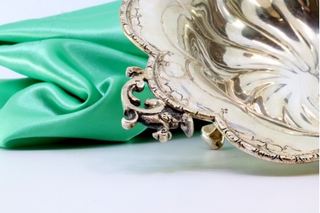 Bomboneira em prata com relevos e aplicações gomadas em formato espiralado e assente em três pés.