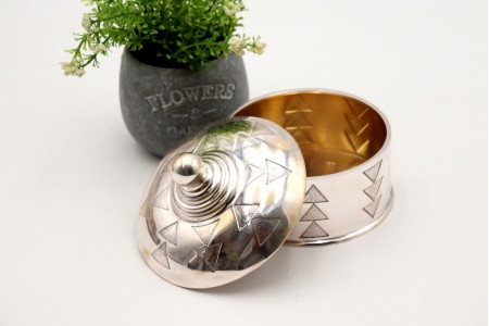 Bomboneira em prata redonda com relevos em forma de triângulos e pomo na tampa frisada