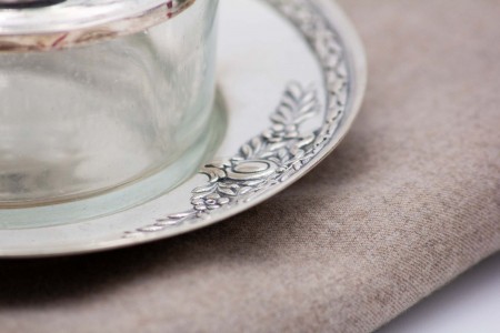 Bomboneira de prata e vidro com pires e relevos alusivos a flores.