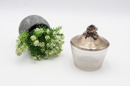 Bomboneira com alma em vidro com friso grego gravado, tampa amovível de prata martelada e pomo em forma de flor.