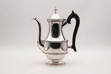 Cafeteira de prata frisos perlados envolventes,  asa em madeira de castanho e base em formato elíptico.