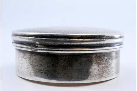   Caixa em prata lisa de forma circular com tampa amovível frisada.