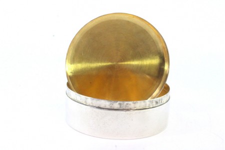 Caixa em prata lisa em forma circular com interior em dourado.