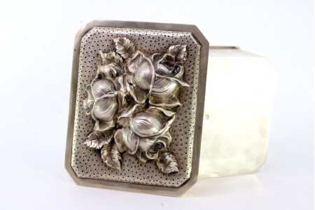 Caixa em prata com flores em alto relevo na tampa amovível e interior dourado.