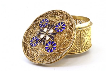 Caixa em prata de filigrana dourada com flores esmaltadas na tampa assente em três pés esféricos.