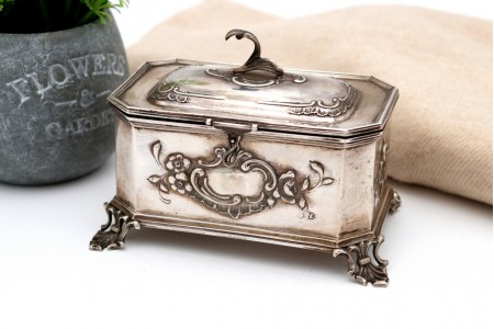 Caixa em prata com relevos pomo na tampa cartela para monograma assente em quatro pés com recortes