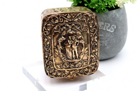 Caixa em prata dourada com relevos idilicos com casal no centro e tampa basculante.