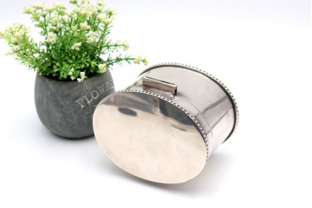 Caixa para chá em prata lisa de formato iliptíco com friso perlado na tampa e base com quatro pés circulares.