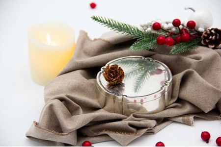 Caixa de prata lisa em formato circular com friso na tampa amovível.