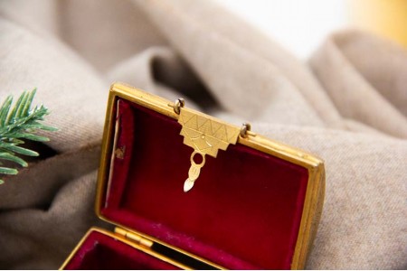 Caixa em prata dourada em formato de baú com gravados, pegas e tampa basculantes com o interior forrado.