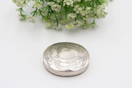 Caixa em prata de forma elíptica com gravados na tampa basculante