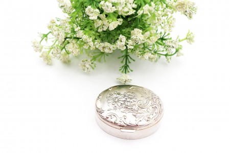 Caixa em prata de forma elíptica com elementos florais em relevo na tampa