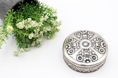 Caixa circular em prata com gravados na envolvência e motivos florais relevados