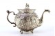  Cafeteira em prata relevada com rostos femininos e duendes, tampa com pomo com figura de leão e assente em quatro pés em forma de garras.