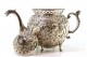  Cafeteira em prata relevada com rostos femininos e duendes, tampa com pomo com figura de leão e assente em quatro pés em forma de garras.