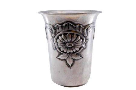 Copo em prata com relevos de flores e folhas na envolvência.