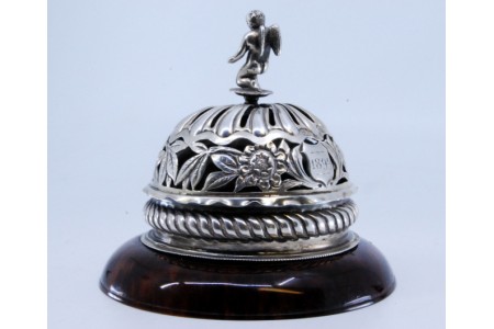  Campainha Vitoriana em prata recortada com cordas, grinaldas, motivos florais, e encimada com anjo assente sobre base em tartaruga.