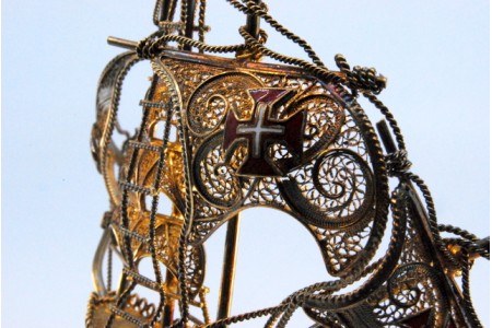 Caravela em  prata filigrana com cruzes esmaltadas nas velas e mastros, assente sobre base recortada.