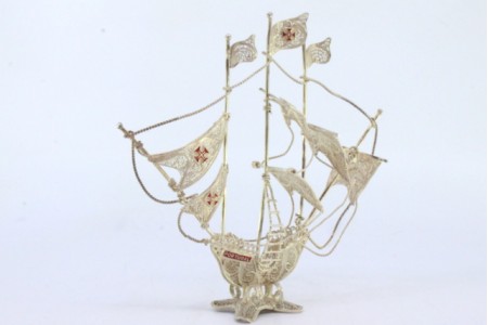 Caravela em prata de filigrana com cruzes esmaltadas nas velas e assente em base com quatro pés.