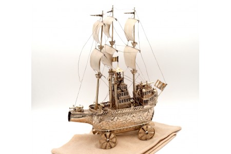 Porta garrafas em prata revelada em forma de caravela com relevos e aplicações