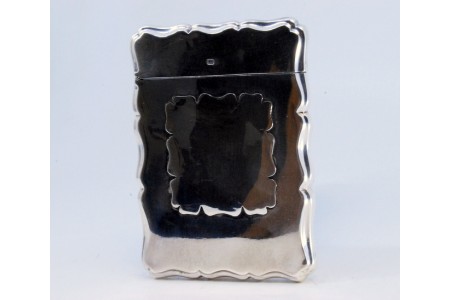 Cartoneira em prata lisa com aplicação ao centro para monograma e contornos ondeados.