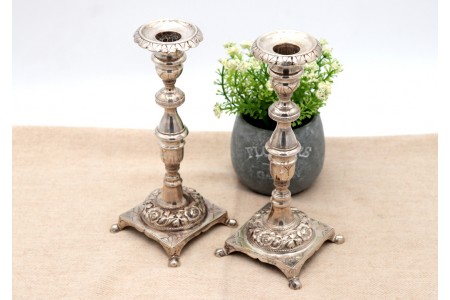 Castiçais de prata com fustes torneados e gravados, assentes sobre bases quadradas com motivos florais relevados.